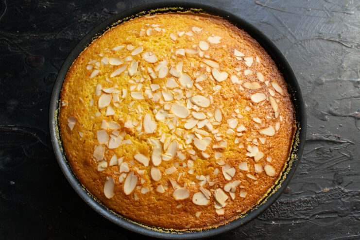 Baking the orange mannik until golden brown and cooked through. The baking pan with the mannik batter placed on the middle rack of an oven.