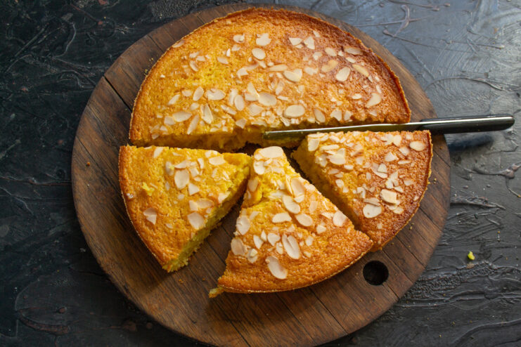 Cooling the freshly baked orange mannik on a wire rack to prevent sogginess. The baked orange semolina cake being transferred from the pan to a wire cooling rack.