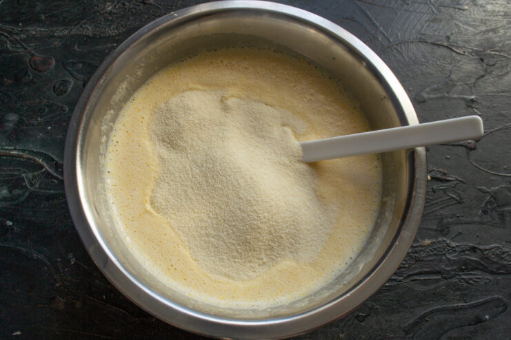 Incorporating semolina, the star ingredient of the mannik cake. Semolina being added to the wet ingredients in the mixing bowl.