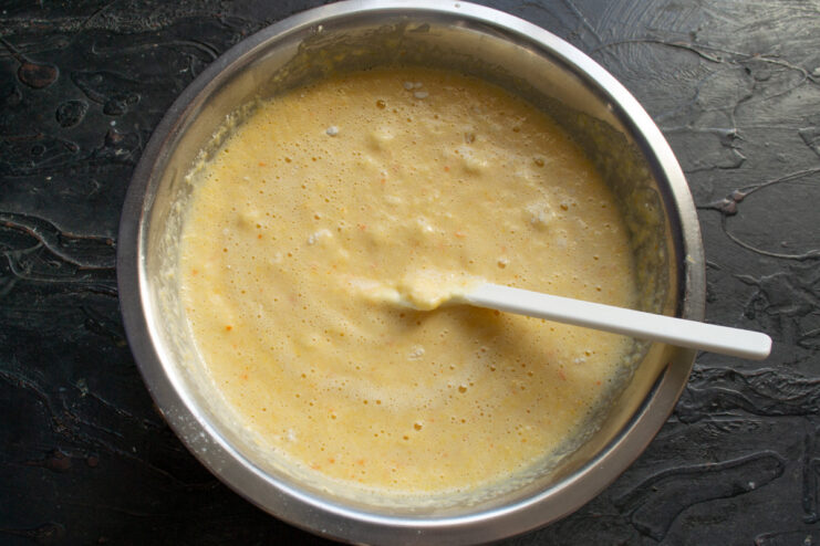 Allowing the batter to rest so the semolina can absorb moisture and swell. The bowl of mannik batter covered and resting on a countertop.