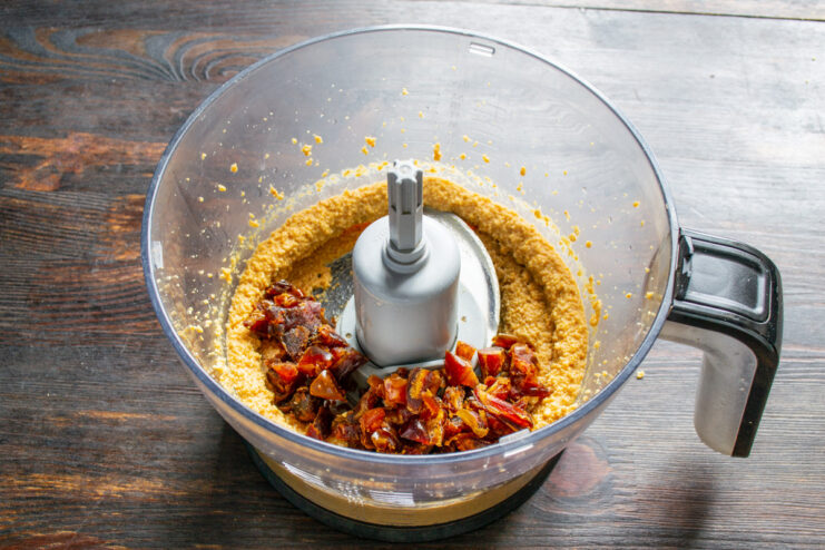 Adding finely chopped dates to the blender Finely chopped dates being added to the peanut mixture in the blender.
