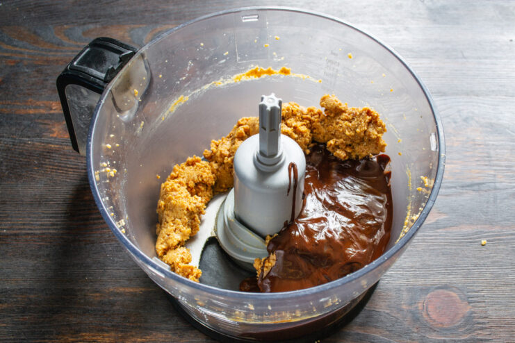 Adding the melted chocolate and honey mixture Melted dark chocolate and honey mixture being poured into the blender with the peanut paste.