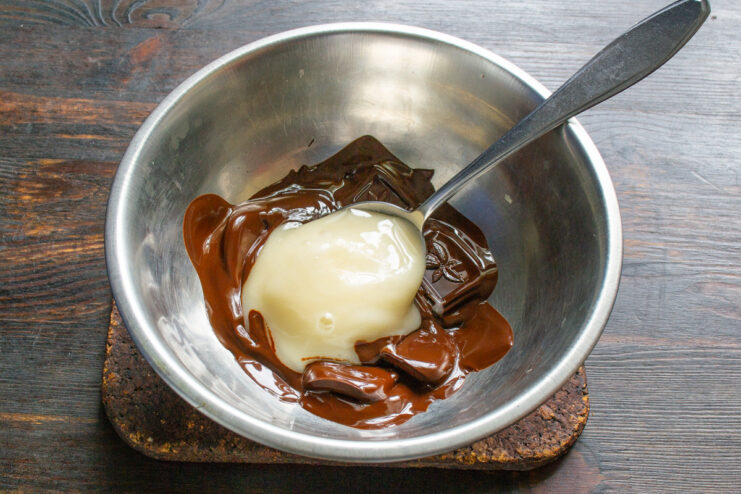 Melting chocolate and honey together for the peanut butter A smooth, glossy mixture of melted dark chocolate and honey in a bowl.