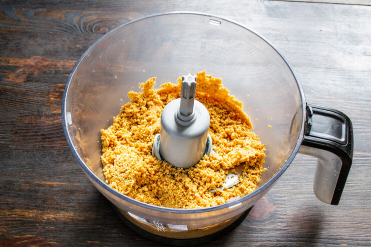 Blending roasted peanuts into a creamy paste Peanuts being processed in a blender, turning into a thick, crumbly paste.