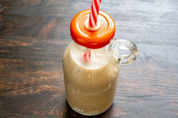 Serving the Freshly Made Peanut Banana Smoothie The finished peanut banana smoothie being poured into a glass bottle with a straw.