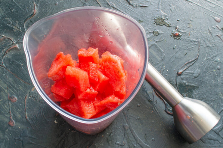 Adding Frozen Watermelon to the Blender Frozen watermelon cubes being placed in a blender jar.