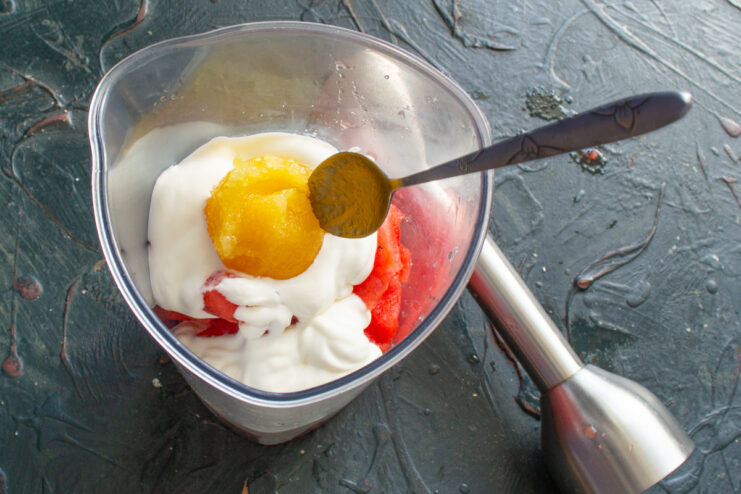 Sweetening the Smoothie with Honey Pouring golden honey into the blender with watermelon and yogurt.