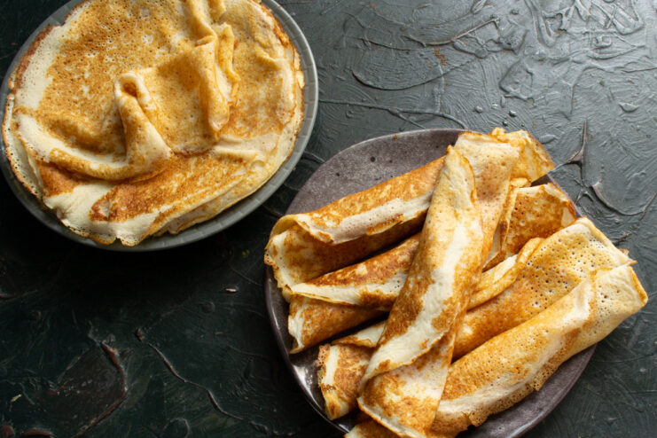 A final presentation of lacy crepes with fruit salad on a plate, ready to be served.