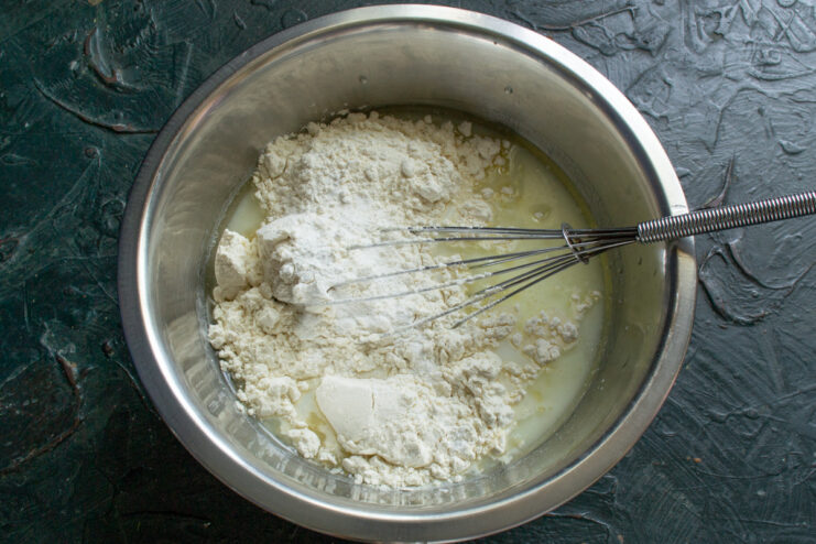 Adding flour, baking soda, and baking powder to the wet ingredients in a bowl.