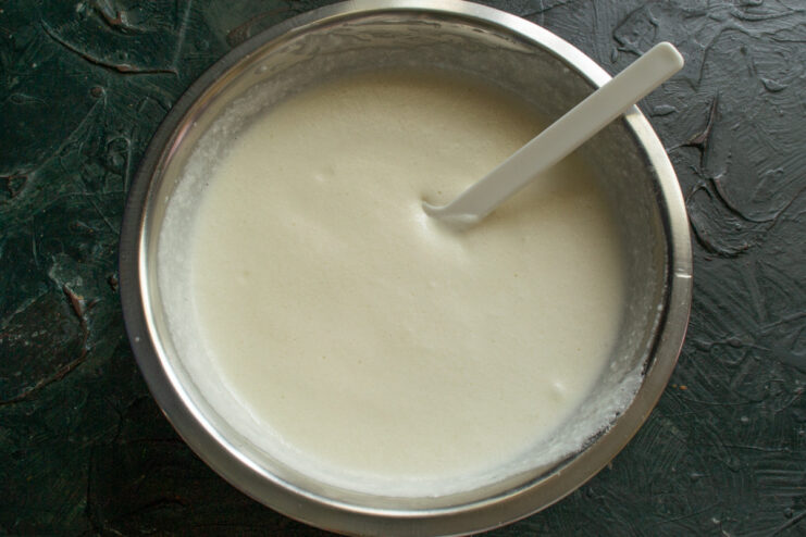 Gently folding whipped egg whites into the crepe batter with a spatula to keep it airy.