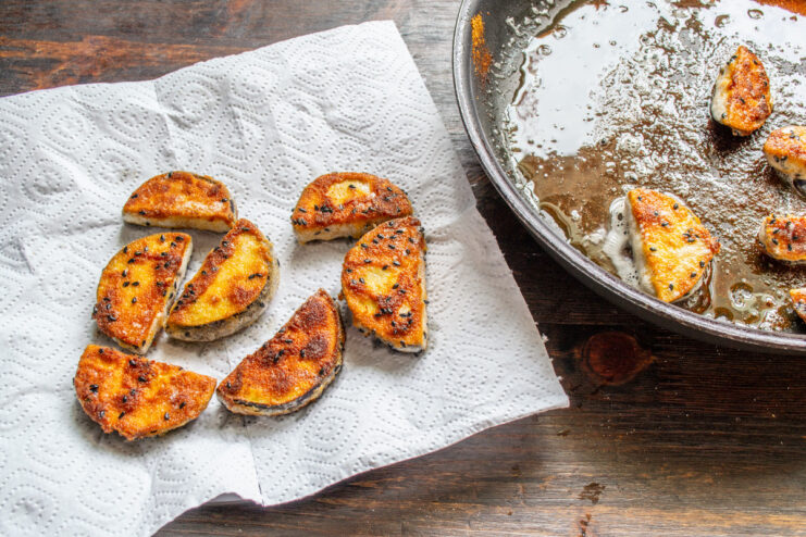 Draining Excess Oil for a Crispier Result Golden-fried eggplant pieces resting on a paper towel to absorb excess oil.