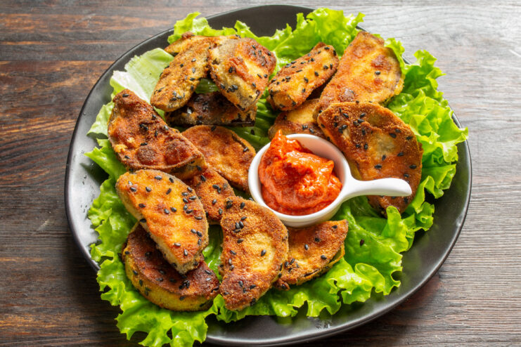 Serving the Crispy Fried Eggplant A final dish of crispy fried eggplant served on a bed of fresh lettuce leaves.