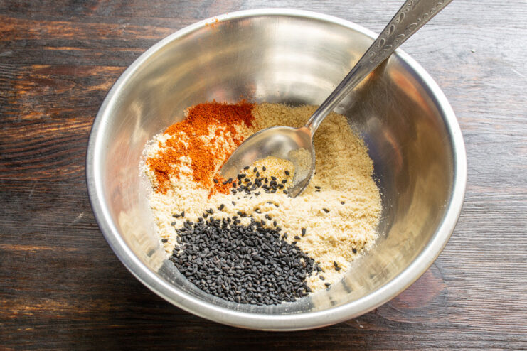 Creating the Perfect Crispy Breading Mix A bowl with breadcrumbs, sesame seeds, and spices being mixed for the breading.