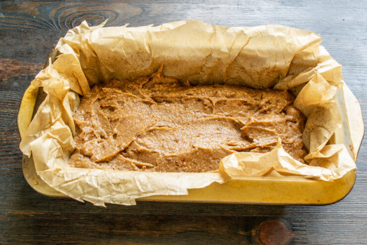 Pouring the batter into a prepared loaf pan Pouring gluten-free banana bread batter into a parchment-lined loaf pan.