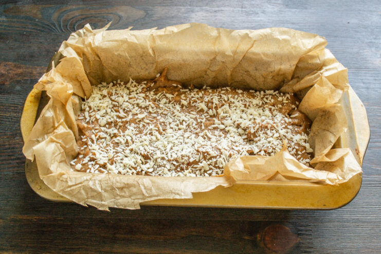 Sprinkling shredded coconut on top for a delicious crust Sprinkling shredded coconut over the banana bread batter in a loaf pan.