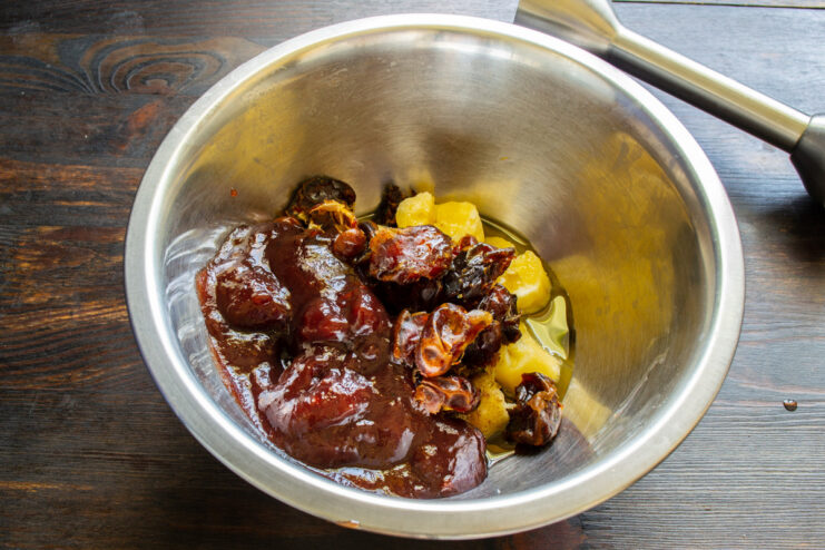 Combining wet ingredients for banana bread: bananas, dates, fruit preserve, and oil A bowl with mashed bananas, dates, fruit preserve, and oil, ready to be mixed.