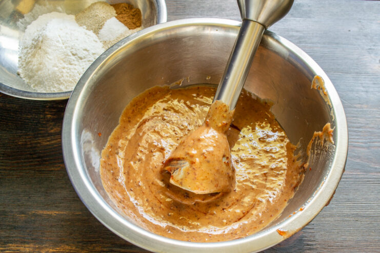 Blending the wet ingredients until smooth for a perfect batter Using an immersion blender to mix banana bread ingredients in a bowl.