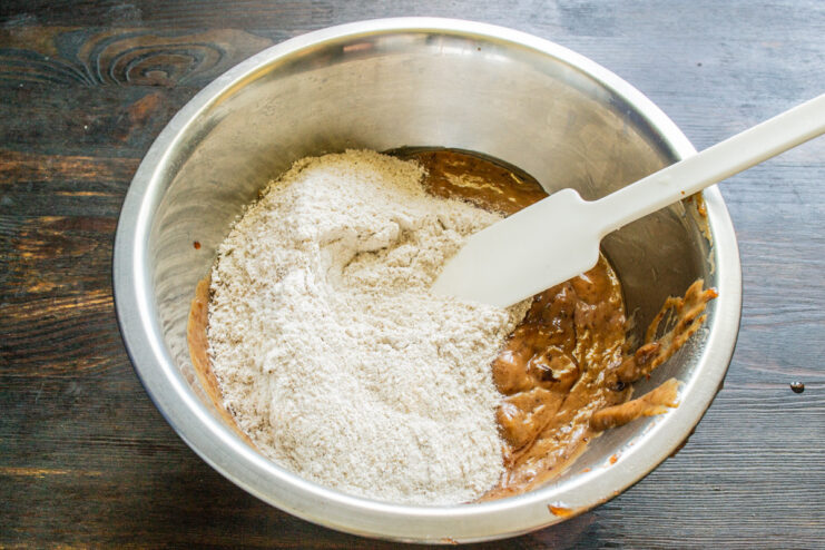 Gradually adding dry flour mixture to the wet ingredients Sifting dry ingredients into the wet mixture for the banana bread batter.