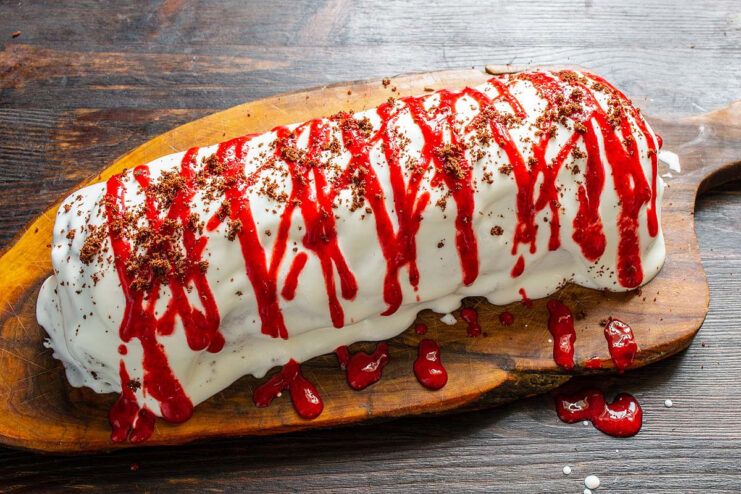Final touches: decorating the roll with more cream and cake crumbs. Decorating the finished sponge roll with piped strawberry cream and cake crumbs.