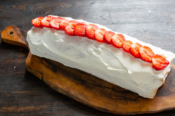 Chilling the Finished Strawberry Sponge Roll Before Serving The fully decorated strawberry and cream sponge roll ready to be chilled in the refrigerator.