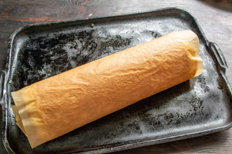 How to Roll the Hot Sponge Cake to Prevent Cracking A freshly baked sponge cake layer being rolled up in parchment paper to cool.