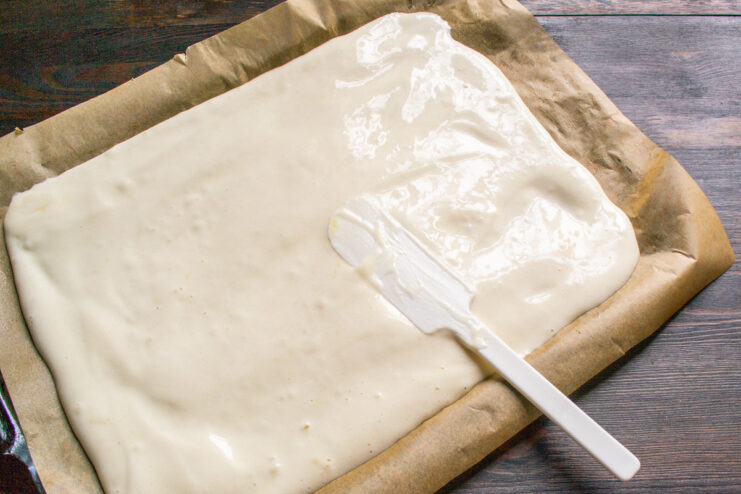 Spreading the Batter on a Baking Sheet Sponge cake batter being spread evenly on a parchment-lined baking sheet.