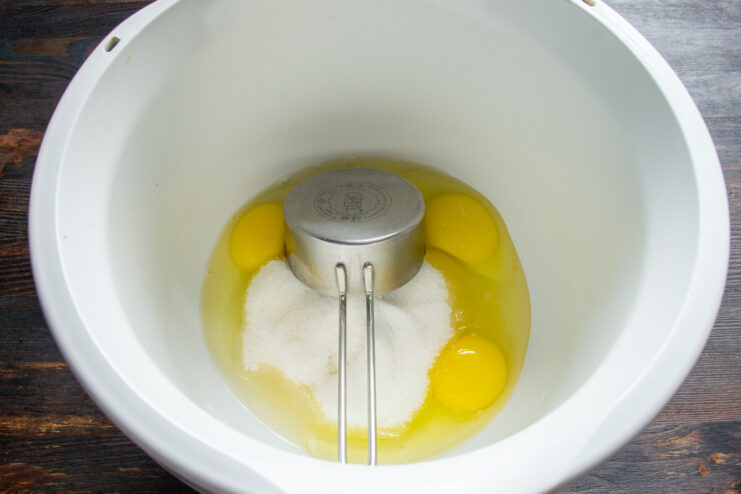 Cracking Eggs into a Mixer Bowl for the Batter Three whole eggs cracked into the glass bowl of a stand mixer.