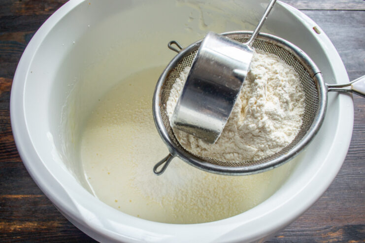 Sifting Flour into the Egg Mixture Sifting all-purpose flour into a bowl with whipped eggs and sugar.