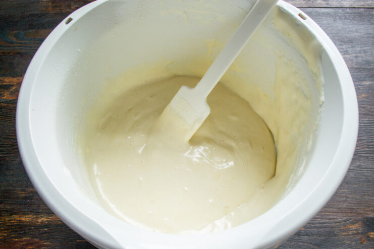 Folding the Batter to a Smooth Consistency A spatula folding flour into the egg mixture to create a smooth sponge cake batter.