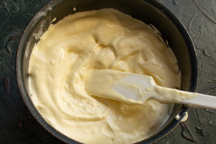 Preparing the Sponge Cake Batter for Baking Sponge cake batter being poured into a round baking pan lined with parchment paper.