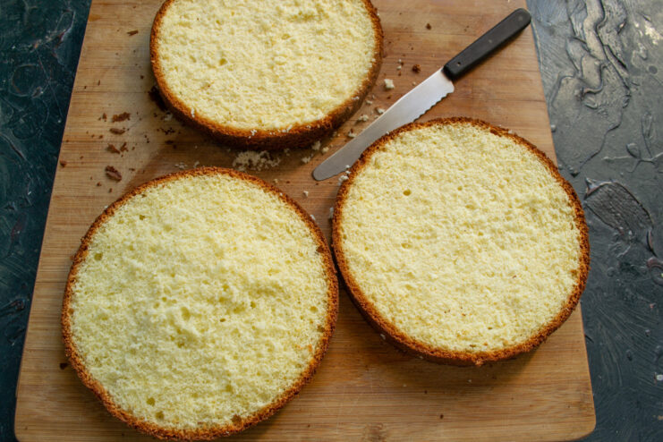 Slicing the Sponge Cake into Three Layers A cooled sponge cake being carefully sliced horizontally into three even layers.
