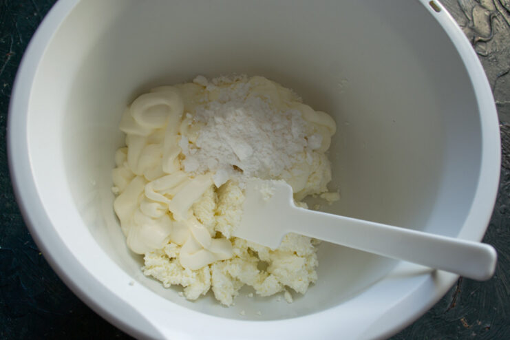 Mixing the Ingredients for the Cottage Cheese Cream Combining cottage cheese, sour cream, and powdered sugar in a bowl for the cream.
