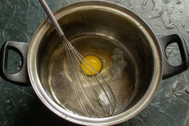 Breaking an Egg to Start the Blinchiki Batter An egg being broken into a bowl with sugar and salt for the blinchiki batter.