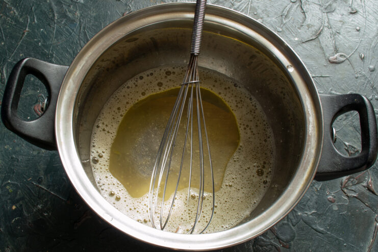 Whisking Rapeseed Oil into the Batter Rapeseed oil being added to the egg mixture in a bowl and whisked.