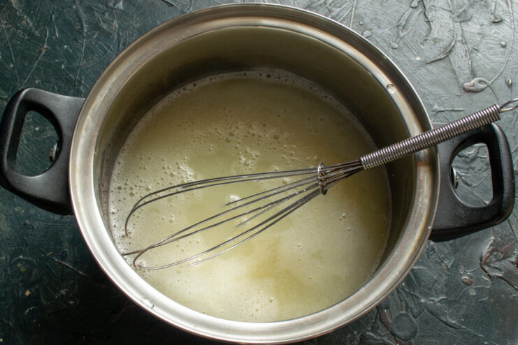 Adding Milk and Water to the Blinchiki Batter Milk and water being poured into the bowl with the batter ingredients.