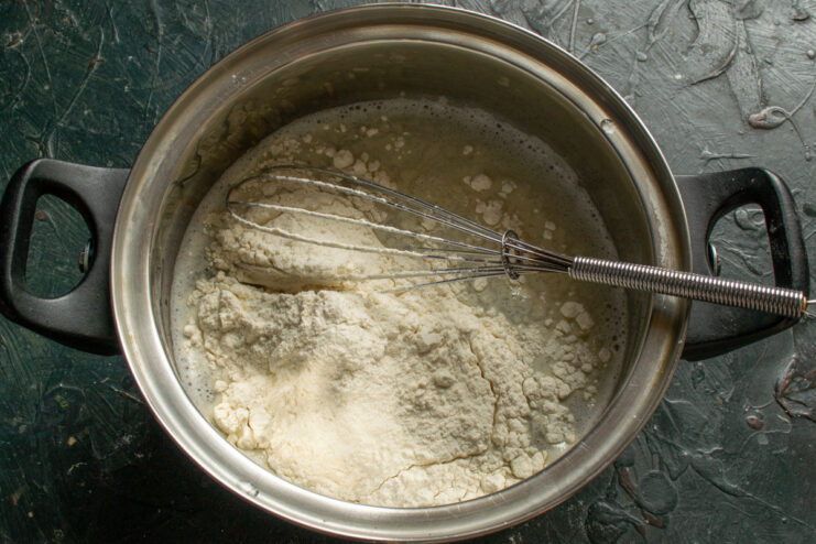Adding Flour to the Pancake Batter Wheat flour being added to the wet ingredients in a bowl to make the batter.