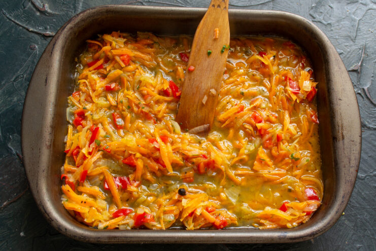 Preparing the baking dish with a layer of vegetable sauce Pouring a savory vegetable sauce into the bottom of a glass baking dish.