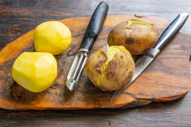 Whole potatoes boiling in a pot of water, cooked in their skins.