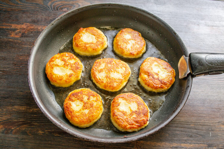 Boxty pancakes frying in a pan, turning a beautiful golden-brown color.