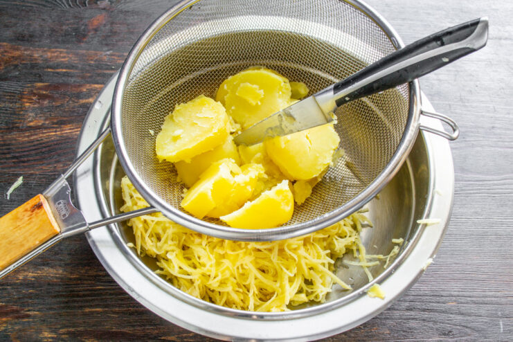 Small cubes of cooked potato in a metal sieve, ready to be mashed.