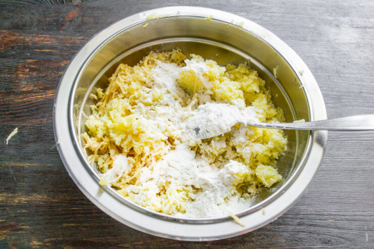Buttermilk being poured from a glass into a bowl with the potato mixture.
