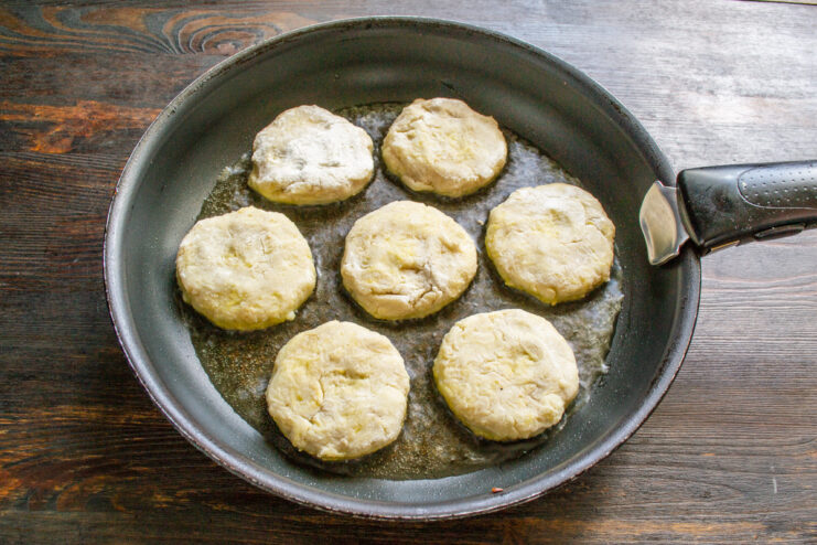 Raw Boxty pancakes being placed into a hot skillet with oil.