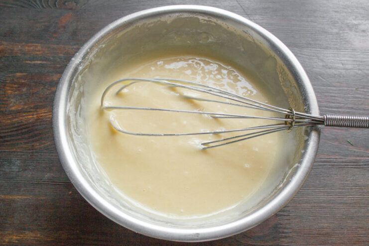 Step 6: Whisking the batter until smooth and lump-free. A smooth, light-yellow batter being mixed with a whisk in a glass bowl.