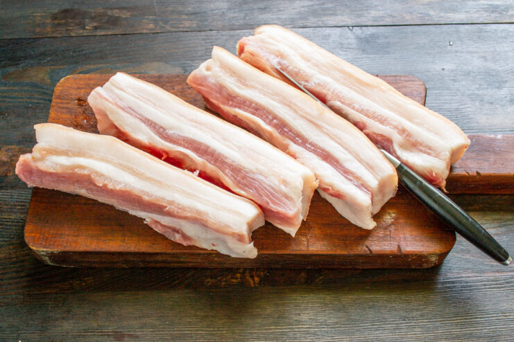 Selecting the perfect cut: Look for skin-on pork belly with lean streaks. A raw piece of skin-on pork belly with visible layers of fat and meat.