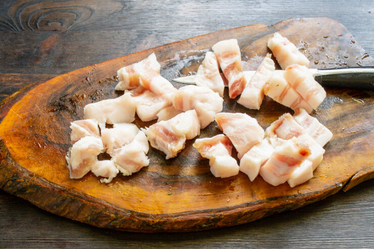 Prepping for the spread: Dicing the cured salo. Cured pork belly being cut into small cubes on a cutting board.