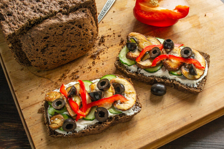 Garnishing the Sandwiches with Sliced Olives Sliced black olives being sprinkled over the mushroom sandwiches.