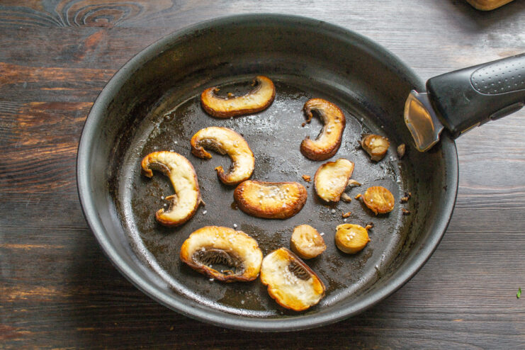 Frying Mushroom Slices Until Golden Brown Mushroom slices frying in a pan until they are golden brown.