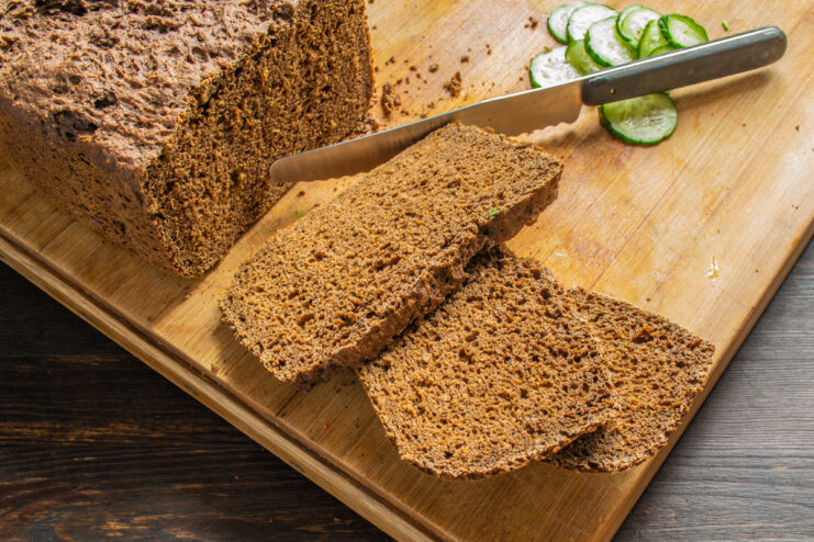 Preparing the Rye Bread Base for the Sandwiches Slicing a loaf of dark rye bread into thin slices.