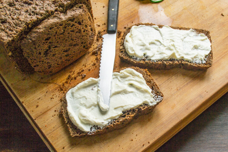 Spreading Cream Cheese on Rye Bread Slices A slice of rye bread being spread with a generous layer of cream cheese.