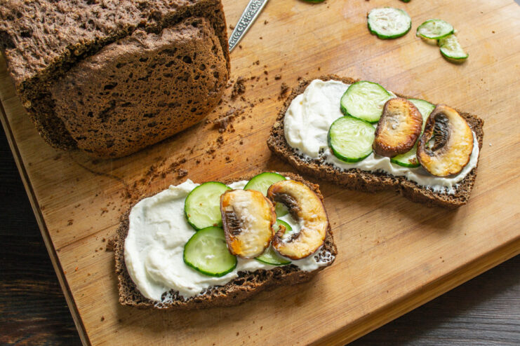 Adding Fresh Cucumber Slices to the Sandwich Thin slices of fresh cucumber being arranged on top of the cream cheese spread.